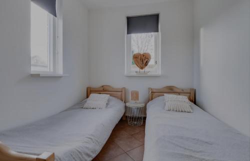 two twin beds in a room with two windows at Huisje Britt met grote tuin en veel privacy in Dirkshorn
