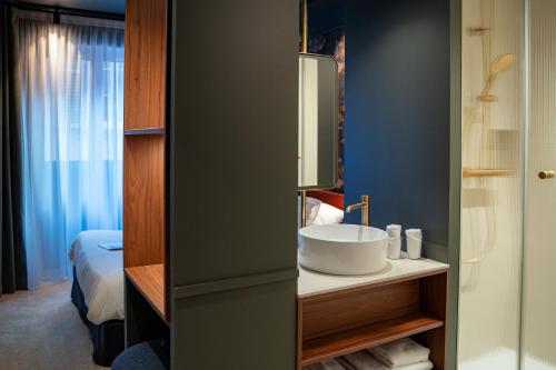 ein Badezimmer mit Waschbecken und Spiegel in der Unterkunft Hôtel Le Rapp in Colmar