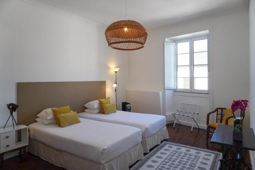 a hotel room with two beds and a window at Canto 30 e UM - HOST & CHILL in Ribeira Grande