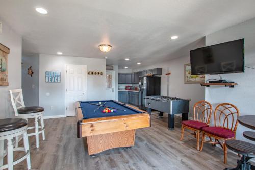 a living room with a pool table and a kitchen at 5469 - Below Deck OBX in Nags Head