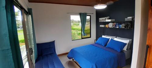 a bedroom with a blue bed and a window at Perla Arenal View in Fortuna