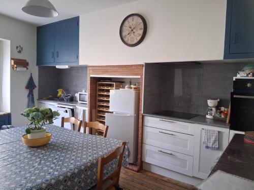 a kitchen with a table and a clock on the wall at La maison du Thoré in Saint-Amans-Valtoret