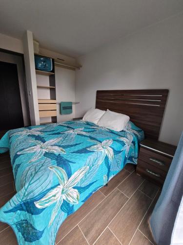 a bedroom with a bed with a blue comforter at Apartamento en Parque Mateo in Guatemala
