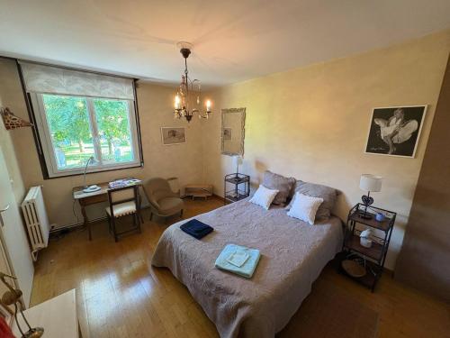 a bedroom with a bed and a desk and a window at Le Petit Baron in Crémieu