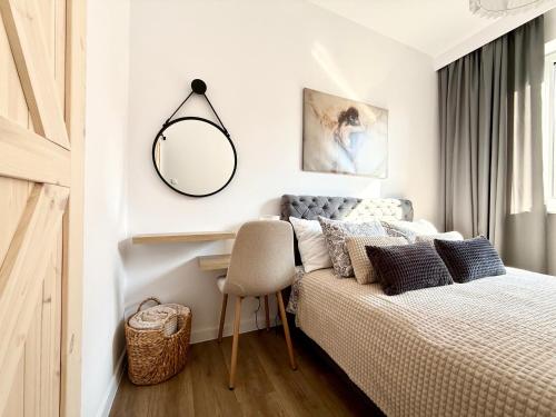 ein Schlafzimmer mit einem Bett, einem Spiegel und einem Stuhl in der Unterkunft Virta 8 in Ostróda