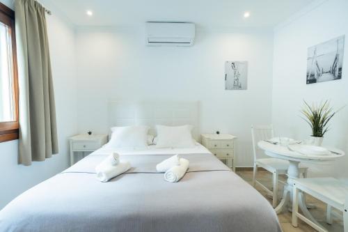 a white bedroom with two beds and a table at Apartamentos Gravina in Tarifa