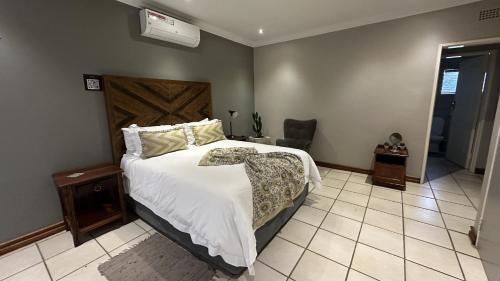 a bedroom with a large bed and a chair at Dessert Rose Guesthouse in Jwaneng