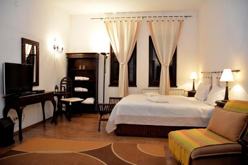 a bedroom with a bed and a desk and a television at Momini Dvori Boutique Guest House in Bansko