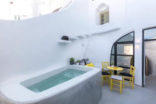 a swimming pool in a white room with a table and chairs at Casa Grande Santorini in Megalochori