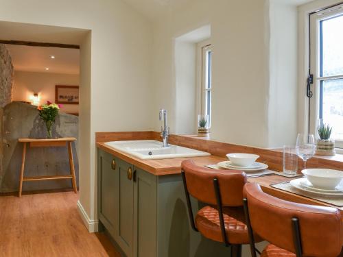 a kitchen with a sink and a table with chairs at The Cowshed - Uk50283 in Earl Sterndale