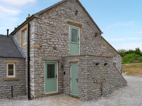 an old stone building with a green door at The Cowshed - Uk50283 in Earl Sterndale