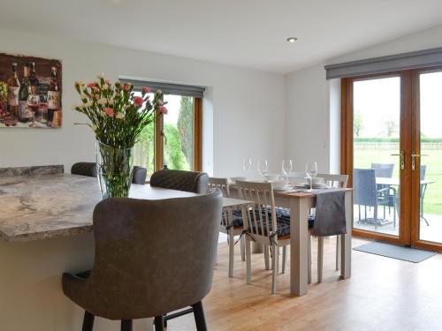 a dining room with a table with chairs and a vase of flowers at Kimberdale Lodge in Great Orton
