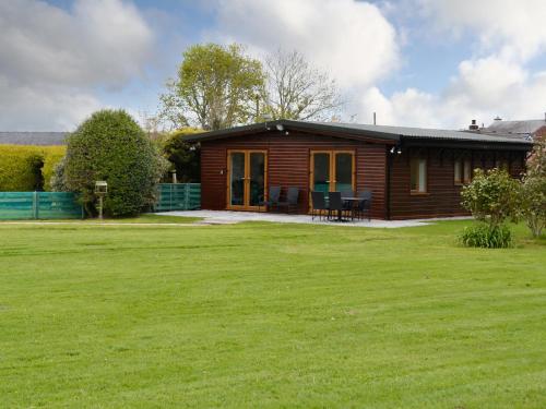 a log cabin with a green lawn in front of it at Kimberdale Lodge in Great Orton