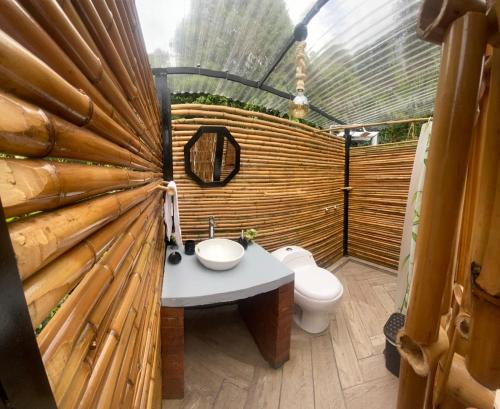 a bathroom with a toilet and a wooden wall at GLAMPING EL PARAÍSO in Sasaima