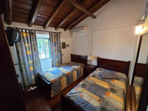 a bedroom with two beds and a window at Casa da Minha Avó in São Pedro de Solis