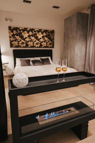 a bedroom with a bed and two glasses of wine at Artemide Resort, Suite Spa Elysia in Lido Di Fondi