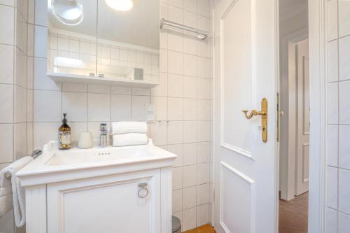 a white bathroom with a sink and a mirror at Beach Bungalow Sylt 1 in Dikjendeel