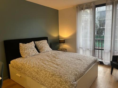 a bedroom with a bed and a large window at STUDIO PROCHE PARIS VERSAILLES in Villennes-sur-Seine