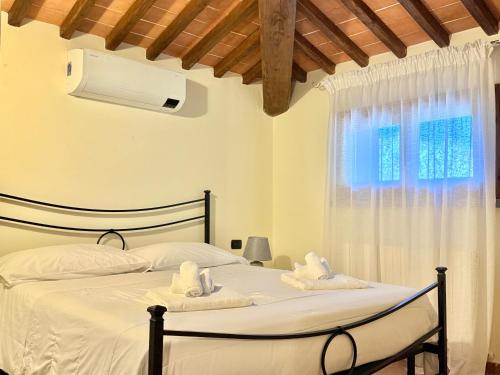 a bedroom with a bed with white sheets and a window at Ville Di Villa Biserno in San Vincenzo