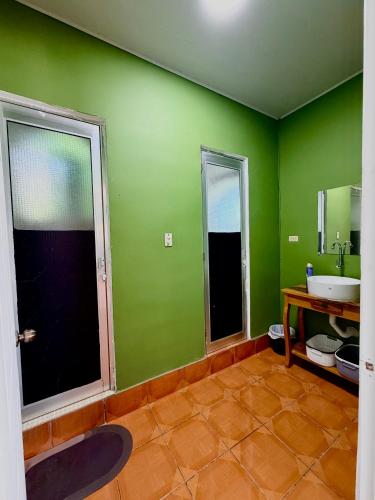 a green bathroom with a sink and a mirror at Casza Grande Alojamiento in La Libertad