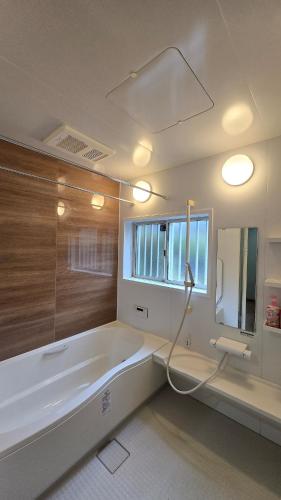 a white bathroom with a tub and a window at 海の風-春 in Wakayama