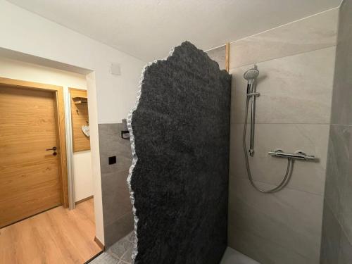 a bathroom with a shower with a stone wall at Appartement Steinblick -Obinghof- in Maishofen