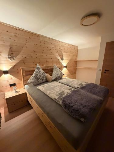 a bedroom with a bed with a wooden wall at Appartement Steinblick -Obinghof- in Maishofen