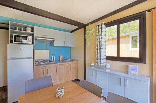 a kitchen with a table and a white refrigerator at Camping 3 étoiles - ccbfggd in Lepin-le-Lac