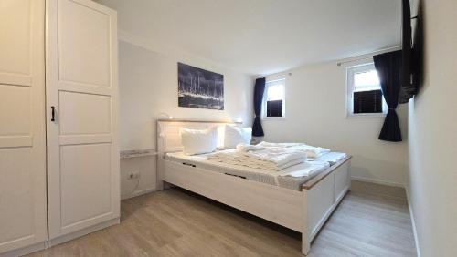 a white bedroom with a bed with white sheets and pillows at Ferienwohnung "Ostseebrise" in Wendtorf in Wendtorf