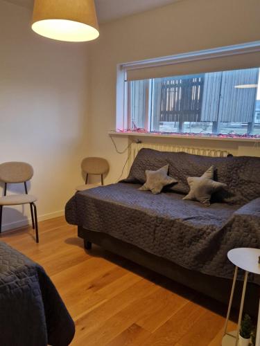a bedroom with a bed with two chairs and a window at SelfossCenter flat in Selfoss
