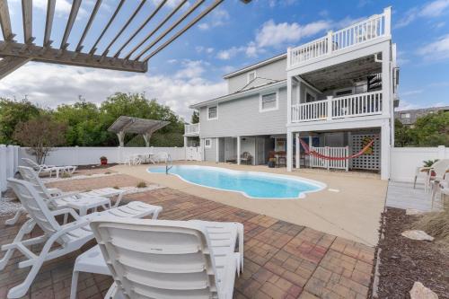 a patio with white chairs and a swimming pool at 4108 - New Beginnings in Duck