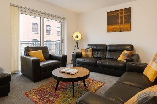 a living room with leather furniture and a table at Waterfront Walk 3 Bedroom Apartment with Parking Pets and Workspace in Dundee