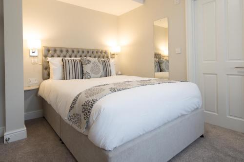 a bedroom with a large white bed and a mirror at The Maple Manor Hotel in Crawley