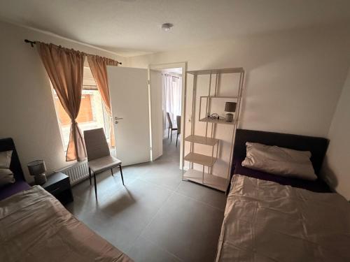 a bedroom with two beds and a chair and a window at Ferienwohnung Cookie in Elxleben