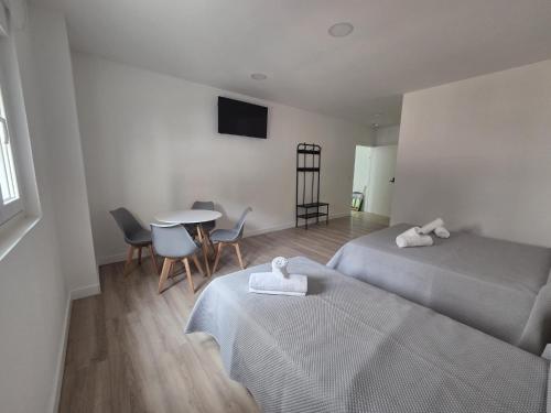 two beds in a room with a table and chairs at Hostal NV Palacio Congresos in Málaga