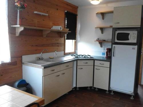 a kitchen with a white refrigerator and a sink at ZEcamping 3 étoiles avec piscine et pataugeoire in Saint-Projet