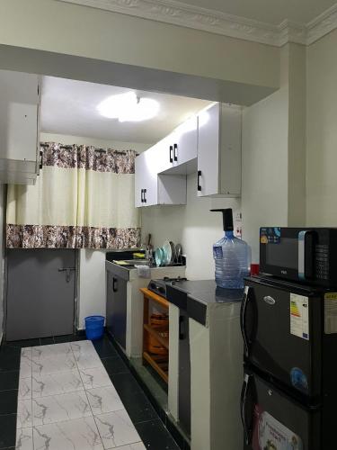 a small kitchen with white cabinets and a microwave at Blissful Homes in Thika
