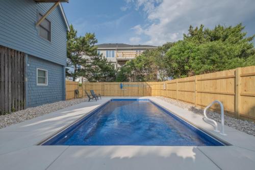 a swimming pool in a backyard with a wooden fence at 3979 - Wright by the Coast in Duck
