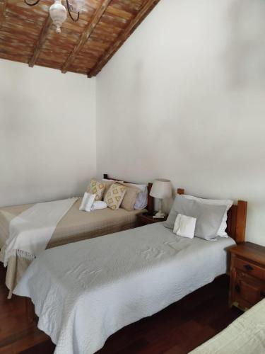 two beds in a bedroom with white walls and wooden floors at Pedacinho do céu in Tiradentes