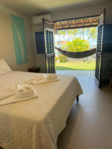 a bedroom with a bed with a view of a garden at Bitingui Praia Hotel in Japaratinga
