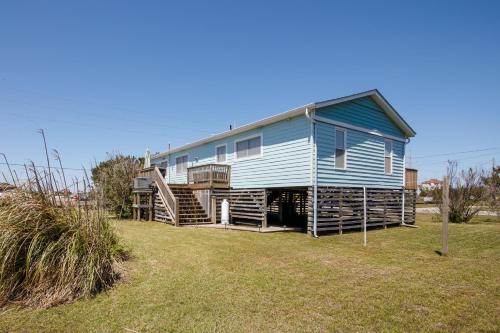 a blue house with a porch and stairs in a yard at 7022 - East Point El Dorado in Rodanthe