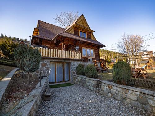 a large wooden house with a stone wall at LookTatry Willa Pod Stokiem Apartments & Jacuzzi in Zakopane