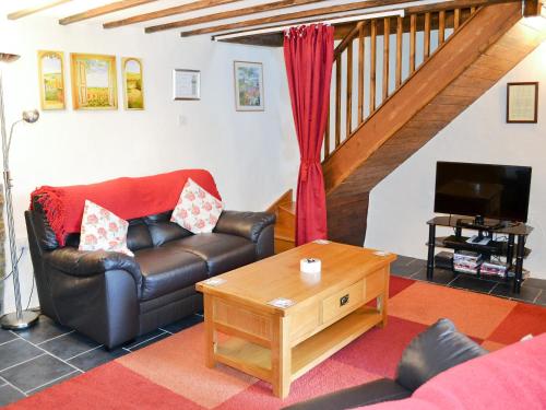 a living room with a leather couch and a table at Fordbrook Cottage in Brixton