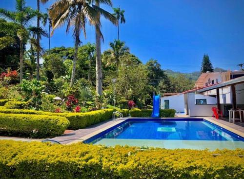 a swimming pool in a garden with trees and bushes at GLAMPING EL PARAÍSO in Sasaima