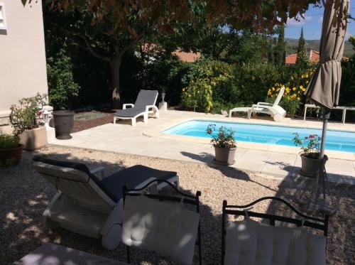 - une piscine avec 2 chaises et un parasol à côté dans l'établissement Chambre D'hôtes Villa de la Sueur au Bonheur, à La Bouilladisse