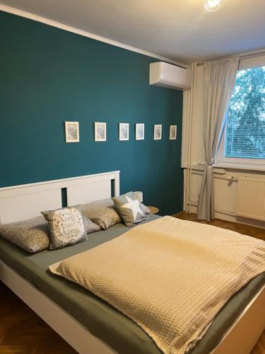 a bedroom with a large bed with a blue wall at Victory apartmán in Šamorín