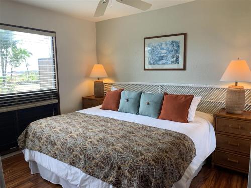 a bedroom with a bed and two lamps and a window at Unit 11 Beautiful Ocean View in Pahala