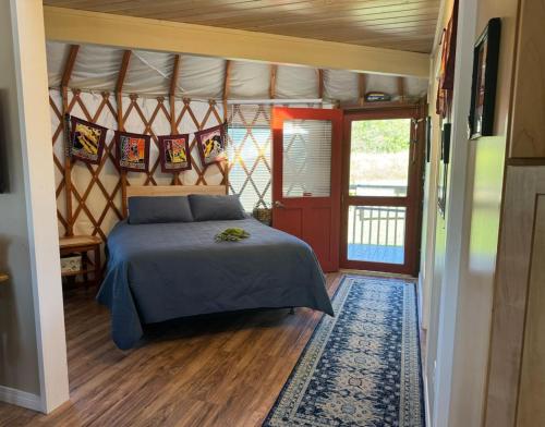 a bedroom with a bed in a room with a door at Yurt BenTiki in Naalehu