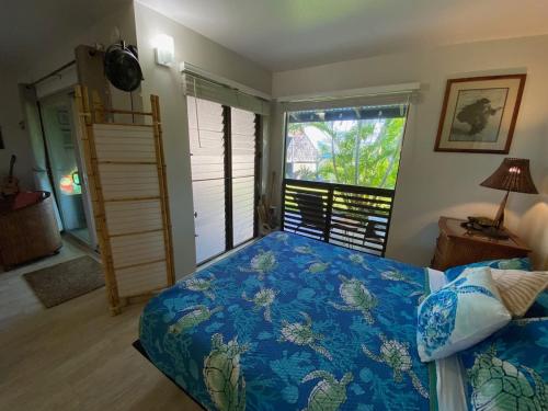 a bedroom with a bed with a blue comforter and a window at 71 Dramatic Ocean and Lava in Pahala