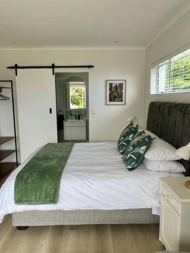 a bedroom with a large white bed with green pillows at Mountain View Studio Hermanus in Hermanus